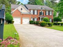 Charming two-story brick home featuring a two-car garage and a well-manicured front yard with lush landscaping at 2049 Mclain Nw Rd, Acworth, GA 30101