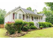 Charming home featuring a welcoming front porch and beautifully landscaped front yard with lush greenery at 68 Paradise Pointe, Douglasville, GA 30134