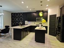 Modern kitchen features dark cabinetry, marble floors, and a stylish island with white countertop at 812 Graeme Dr, Mcdonough, GA 30252