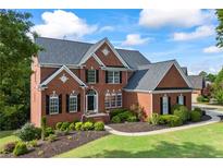 Charming two-story brick home with a manicured lawn and classic architectural details at 5260 Harbury Ln, Suwanee, GA 30024
