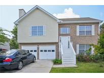 Charming two-story home with brick and vinyl siding, attached garage, and well-maintained front yard at 7169 Sweet Gum Ct, Lithonia, GA 30058