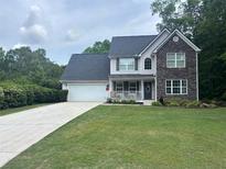 Charming two-story home with a manicured lawn, a two-car garage and a welcoming front porch at 1020 Travitine Trl, Loganville, GA 30052