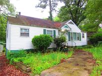 View of a one story home with green shutters, overgrown grass, and a driveway at 244 Hilltop Sw Dr, Atlanta, GA 30315