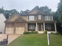 Charming two-story home with stone accents, covered front porch, and a manicured lawn at 6725 Grove Meadows Ln, Cumming, GA 30028