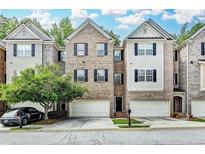 Charming townhome featuring a brick facade, attached garage, and neatly landscaped front yard at 2173 Pebble Beach Dr, Lawrenceville, GA 30043
