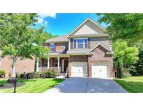 Two-story brick home featuring a manicured lawn, an attached garage, and a covered porch at 4885 Maristone Landing Way, Cumming, GA 30040