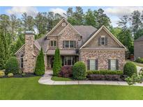 Stately brick home featuring manicured landscaping, a stone chimney, and classic architectural details at 390 Scott Farm Dr, Powder Springs, GA 30127