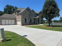 Stunning stone and siding home with a spacious three-car garage and long driveway to a water view at 4010 Sierra Knolls Ct, Cumming, GA 30040