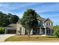 Beautiful stone and siding two-story home with a three-car garage and professionally landscaped yard at 4010 Sierra Knolls Ct, Cumming, GA 30040
