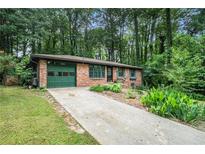 Charming brick home features a well-manicured lawn, landscaping, and an attached garage at 1094 Seville Dr, Clarkston, GA 30021