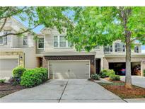Charming townhome featuring a two-car garage, brick accents, and lush green landscaping at 3123 Cross Creek Dr, Cumming, GA 30040