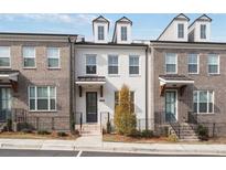 Charming townhome featuring brick and painted facade, dormer windows, and professionally landscaped front yard at 1309 Bennett Creek Ovlk, Suwanee, GA 30024