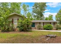 Charming one-story home with a well-manicured lawn and mature trees and a green front door at 7370 N Mitchell Ct, Villa Rica, GA 30180