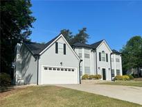 Charming two-story home with gray siding, attached garage, and manicured lawn at 6940 Treeline Dr, Cumming, GA 30028
