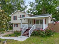 Charming two-story home featuring a welcoming front porch with red accents and blossoming roses at 2100 Rockies Ct, Norcross, GA 30071