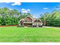 Charming two-story home with stone and shake siding, lush lawn, and mature trees in a beautiful setting at 100 Chantilly Ln, Fayetteville, GA 30215