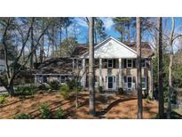 Classic two-story brick home with white columns and a symmetrical facade surrounded by mature trees and landscaping at 6300 Mountain Brook Ln, Atlanta, GA 30328