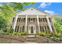 Elegant brick home with stately white columns and a beautifully landscaped front yard creates a welcoming entrance at 6300 Mountain Brook Ln, Atlanta, GA 30328