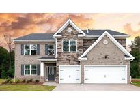 Beautiful two-story home showcasing a blend of brick and stone, complemented by a two-car garage and welcoming front door at 133 Canal St, Hampton, GA 30228