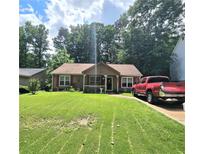 Charming single-story home featuring a lush green lawn, complementing the cozy architecture and inviting curb appeal at 107 Honeysuckle Ln, Stockbridge, GA 30281