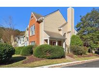 A charming townhome featuring a mix of brick and beige siding, complemented by mature landscaping at 3050 Camden Way, Alpharetta, GA 30005