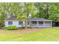 Charming single-story home with a screened front porch and a lush, tree-filled yard and dual carports at 4507 Laurie Ln, Powder Springs, GA 30127