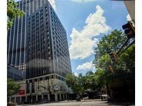 The building's exterior showcases modern architecture against a backdrop of trees and a blue sky with clouds at 20 Marietta Nw St # 10 F, Atlanta, GA 30303