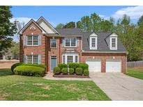 Charming brick home with a well-manicured lawn, blue door, and two-car garage at 4535 Howell Farms Nw Rd, Acworth, GA 30101