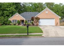 Charming brick home featuring a manicured lawn, mature trees, and a two-car garage at 1520 Great Oaks Dr, Lawrenceville, GA 30045