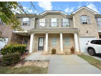 Charming townhome featuring a brick and gray facade, a covered porch, and a well-maintained lawn at 1560 Iris Walk, Jonesboro, GA 30238
