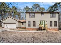 Charming two-story home with light siding, brick foundation, and a lovely green front door and matching trim at 1791 Lake George Dr, Lithia Springs, GA 30122