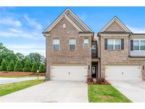 Two-story brick townhome featuring a two-car garage and a well-manicured front yard at 2170 Trelipe Dr, Lawrenceville, GA 30044