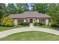 Elegant one-story home features a circular driveway, manicured lawn, and lush landscaping at 194 Sentinel Se Pl, Marietta, GA 30067