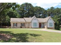 Charming brick home with manicured lawn, mature trees, and a welcoming red front door at 1311 N Brandy Se Shls, Conyers, GA 30013
