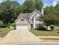 Charming two-story home features a manicured lawn, attached garage, and traditional architectural details at 307 Lee Miller Dr, Suwanee, GA 30024