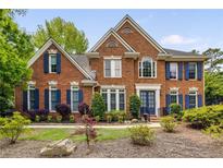 Stately brick home featuring a symmetrical facade, manicured lawn, and charming blue shutters at 710 Devon Hill Ct, Roswell, GA 30075