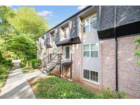 Brick and siding exterior of townhome with manicured lawn and black trim and stair railing at 305 Winding River Village Dr # F, Atlanta, GA 30350