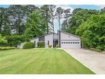 Charming gray home with manicured lawn and two-car garage nestled among mature trees at 5697 Brooklyn Ln, Norcross, GA 30093