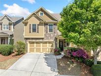 Charming two-story home features a stone facade, well-maintained landscaping, and a two-car garage at 8360 Village School Dr, Cumming, GA 30041