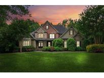 Charming two-story home with brick and stone accents, lush landscaping, and a well-manicured lawn at sunset at 2840 Astoria Ave, Cumming, GA 30040