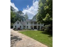Charming two-story home with a white exterior, inviting front porch, and well-manicured lawn, framed by lush greenery at 1042 Trailridge Pl, Atlanta, GA 30338