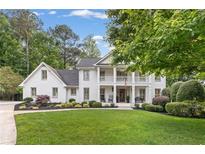 Charming white brick home boasts a manicured lawn, lush landscaping, and a welcoming front porch at 1042 Trailridge Pl, Atlanta, GA 30338
