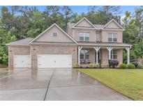 Charming two-story brick home with a three-car garage and well-manicured lawn and a cozy porch at 6179 Ashbranch Dr, Acworth, GA 30101