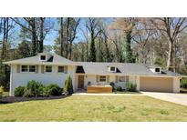 Charming ranch-style home with white painted brick, dormers, manicured lawn and mature trees at 1978 Fisher Trl, Atlanta, GA 30345