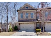 Charming brick townhome featuring a two-car garage, well-maintained landscaping, and classic architectural details at 2006 Towneship Trl, Roswell, GA 30075