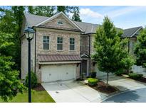 Charming townhome showcasing a brick facade, two-car garage, and manicured landscaping at 2006 Towneship Trl, Roswell, GA 30075