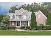 Charming two-story home with a manicured lawn, brick and stone accents, and mature trees at 414 Candler Trl, Canton, GA 30115