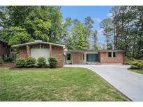 Charming brick home featuring a well-manicured lawn and a long driveway in a serene, wooded setting at 4469 Huntington Cir, Atlanta, GA 30338