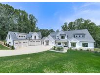 Stunning white farmhouse-style home with a spacious lawn, and a five-car garage nestled among mature trees at 106 Belmont Dr, Canton, GA 30115