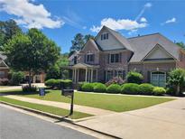 Beautiful brick home with manicured lawn and mature landscaping, complemented by a clear blue sky at 1758 Rosehedge Nw Way, Kennesaw, GA 30152